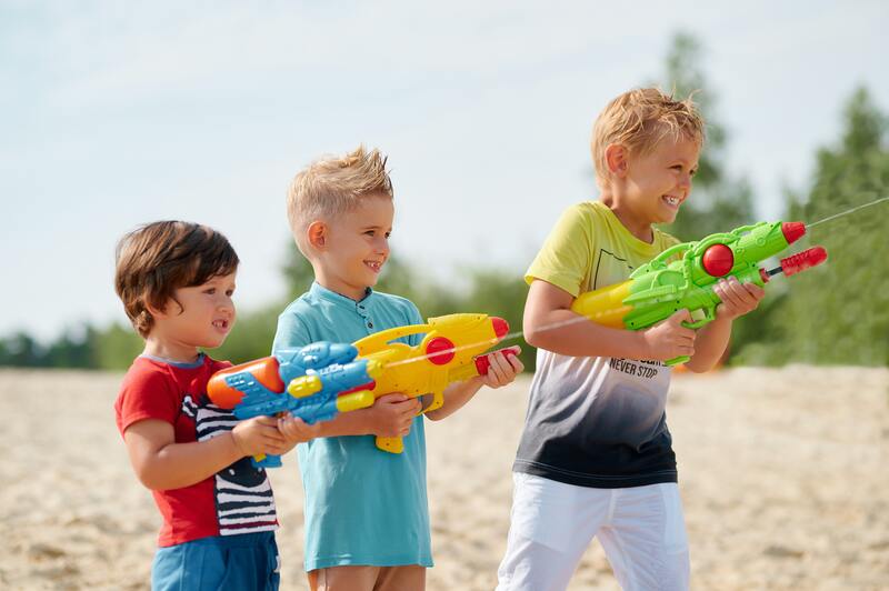 Picture of three boys under 10 years old playing with water pistols at the beach. They are smiling and having fun shooting water at each other at Hervey Bay Beach near Pinnacle estate.